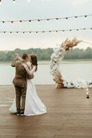 le premier mariage Danse de le la mariée et jeune marié sur le jetée près le rivière photo