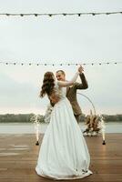 le premier mariage Danse de le la mariée et jeune marié sur le jetée près le rivière photo