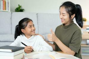 mère enseignement leçon pour fille. asiatique Jeune peu fille apprendre à maison. faire devoirs avec gentil mère aider, encourager pour examen.. fille content école à la maison. maman Conseil éducation ensemble. photo