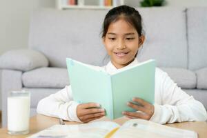 fille apprendre à maison. faire devoirs, encourager pour examen. Asie fille content école à la maison, éducation, pratique, technologie livre, étude, enfant, cours pour asiatique les enfants photo