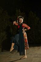 une Javanais Danseur portant une noir châle et jasmin sur sa tête tandis que dansant sur étape à nuit photo