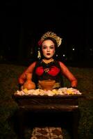 large coup de un asiatique fille dans traditionnel vêtements séance dans une forêt avec une table plein de fleurs photo