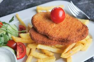 poulet schnitzel servi avec Patate frites photo