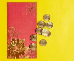 Haut vue de rouge enveloppes avec d'or pièces de monnaie sur Jaune couverture avec personnalisable espace pour texte photo