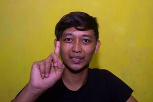 gresik, Indonésie, 5 décembre 2023 - le expression de une Jeune homme montrant le code nombre un avec le sien indice doigt. photo