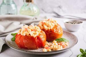 cuit tomate moitiés rempli avec brouillé Oeuf et basilic sur une assiette sur le table photo