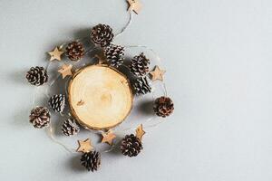 Noël arrière-plan, guirlande et pin cônes autour une Couper arbre tronc sur gris photo