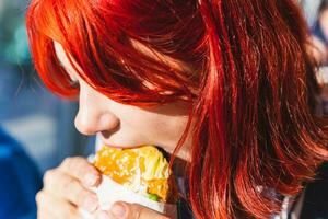 Jeune femme profiter une savoureux gourmet Burger avec Frais herbes et sésame des graines photo