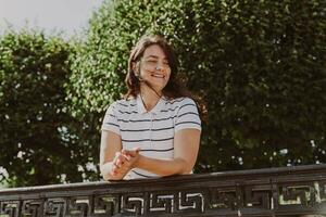 souriant âge moyen Dame avec longue cheveux pose dans Urbain verdure photo