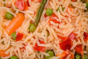 délicieux bouilli riz avec des légumes poivrons, vert petits pois, sel, épices et herbes photo