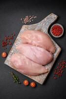 filet de poulet frais sur une table en béton foncé avec des épices et des herbes photo