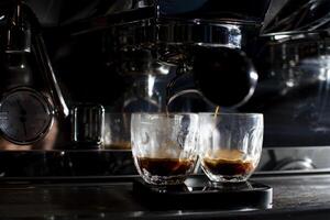 la machine à café fait un double expresso dans des verres la nuit, le processus de préparation du café, en gros plan