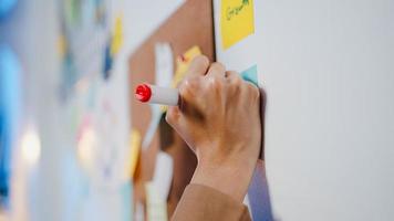 groupe de jeunes hommes d'affaires d'asie discutant d'une réunion de brainstorming d'entreprise travaillant ensemble en partageant des données et en écrivant un tableau blanc sur le mur avec une note collante au bureau de nuit. concept de travail d'équipe de collègue. photo