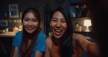 les femmes d'asie adolescentes se sentent heureuses en souriant selfie et regardent la caméra avec se détendre dans le salon la nuit à la maison. appel vidéo de dames colocataires gaies avec un ami et la famille, concept de femme de style de vie à la maison. photo