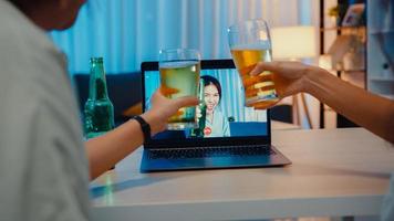 jeune femme asiatique buvant de la bière s'amusant heureux moment de fête de nuit événement en ligne célébration par appel vidéo dans le salon de la maison la nuit. distanciation sociale, quarantaine pour la prévention des coronavirus.