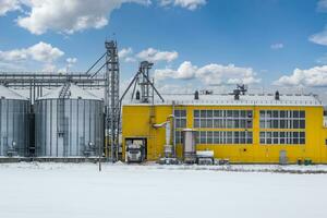 moderne agro-industrie plante pour En traitement et silos pour séchage nettoyage et espace de rangement de agricole des produits, farine, céréales et grain dans neige de hiver champ photo