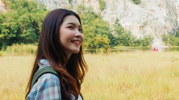 joyeuse jeune voyageuse asiatique avec sac à dos marchant au bord du lac de montagne. Une adolescente coréenne profite de son aventure de vacances en se sentant heureuse de la liberté. voyage de style de vie et détendez-vous dans le concept de temps libre.