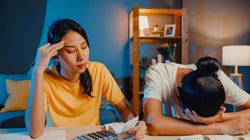 stress asie couple homme et femme utilisent la calculatrice pour calculer le budget familial, les dettes, les dépenses pendant la crise économique financière à la maison la nuit. problème d'argent de mariage, concept de plan de budget familial. photo