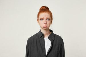 une Jeune roux fille regards en haut avec tristesse, fait ne pas trouver sa Nom sur le liste, a été en retard pour le nommé temps, dépeint un insulte, renfrogné et collage en dehors sa inférieur lèvre photo