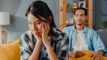 une femme de couple asiatique bouleversée s'asseoir sur un canapé écouter un mari furieux crier se sentir malheureux lui parler négativement. couple a une dispute ou un désaccord à la maison, problème de couple, relation toxique familiale mariée. photo