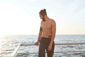 grands Matin portrait de Jeune sportif homme avec barbe, du repos après le jogging à le bord de mer, Ecoutez préféré mélanger sur écouteurs. photo