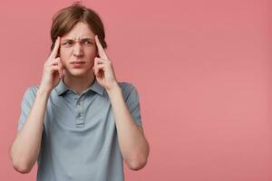 proche en haut Jeune homme pensée, en essayant difficile à rappelles toi quelque chose à la recherche concentré à le côté droit sur Vide espace de copie, les doigts sur les temples isolé rose Contexte. négatif émotion faciale expressions photo