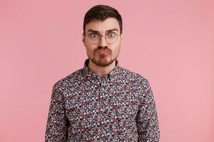 portrait de Jeune Beau barbu homme avec un en colère, agressif faciale expression, prêt pour le lutte, montrant furieuse et belligérant, plus de rose mur photo