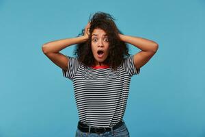 étourdi effrayé femme se souvient quelque chose formidable, garde tous les deux mains sur diriger, garde mâchoire abandonné, porte dépouillé T-shirt, dit oh mon Dieu, il pouvez ne pas être donc personnes, négatif émotions et sentiments concept. photo