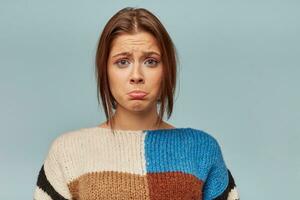 proche en haut de émotif femme avec une triste expression sur affronter, courbé inférieur lèvre avec une mécontent regarder. le fille reçu mal mots à propos sa travail, se sent déçu, isolé plus de bleu Contexte photo