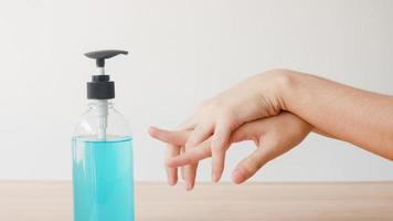 femme asiatique utilisant un désinfectant pour les mains au gel d'alcool se laver les mains pour protéger le coronavirus. une femme pousse une bouteille d'alcool pour nettoyer la main pour l'hygiène lorsque la distanciation sociale reste à la maison et le temps d'auto-quarantaine. photo