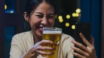 jeune femme asiatique buvant de la bière s'amusant moment heureux fête du nouvel an événement en ligne célébration par appel vidéo par téléphone à la maison la nuit. distanciation sociale, quarantaine pour la prévention des coronavirus. photo