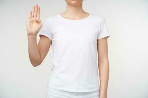 photo de Jeune femme apprentissage sourd alphabet et formant lettre b avec élevé main, étant isolé plus de blanc Contexte dans blanc de base T-shirt