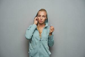 intérieur photo de sportif Jeune blond femme avec décontractée coiffure habillé dans athlétique porter avec capuche