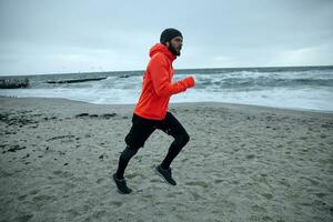 côté vue de Jeune Beau actif barbu homme profiter Matin jonglage sur Frais du froid temps, écoute à préféré la musique liste tandis que Faire Matin des exercices Extérieur photo