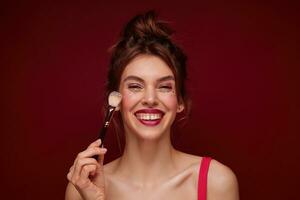 content Jeune marron aux cheveux charmant femme avec de fête maquillage portant décontractée coiffure tandis que permanent plus de Bourgogne arrière-plan, réunion avec copains dans soir et étant dans haute esprit photo