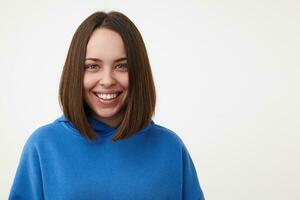 intérieur photo de Jeune content marron aux cheveux femme avec court la Coupe de cheveux montrant sa parfait blanc les dents tandis que souriant gaiement, isolé plus de blanc Contexte