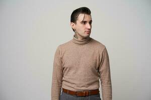 intérieur photo de Jeune à la mode foncé aux cheveux homme avec tatouage sur le sien cou portant branché coiffure tandis que posant plus de blanc arrière-plan, à la recherche de côté et en gardant mains vers le bas