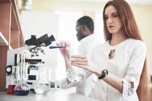 les laboratoires de laboratoire mènent des expériences dans un laboratoire de chimie dans des flacons transparents. formules de sortie photo