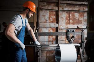 portrait d'un jeune travailleur portant un casque de sécurité dans une grande usine métallurgique. l'ingénieur sert les machines et fabrique des pièces pour les équipements à gaz photo