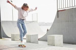 une jeune femme sportive qui monte dans un parc sur une planche à roulettes. photo