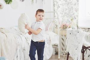 petit garçon en chemise blanche avec oreiller. bataille d'oreillers photo