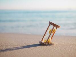 Sablier sur le plage dans le le coucher du soleil temps. le concept à propos compte à rebours à été, voyage, vacances et relaxation. photo