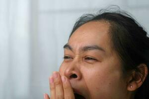 fatigué femme bâillement couvrant sa bouche avec sa mains vouloir à repos. portrait de asiatique femme avec négatif expression, fatigué, bâillement, couvrant sa bouche avec mains dans décontractée vêtements. photo