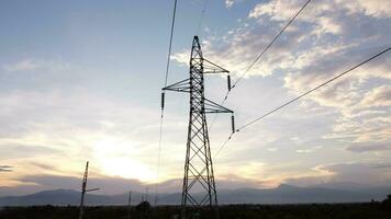 vue aérienne des pylônes et des fils à haute tension dans le ciel au coucher du soleil dans la campagne. images de drones de poteaux électriques et de fils au crépuscule. photo