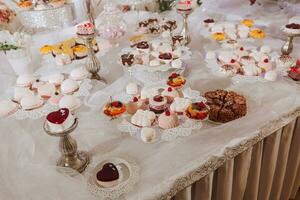 de fête dessert table avec bonbons. mariage bonbons bar, divers Gâteaux, des chocolats sur des stands. photo