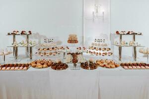 de fête dessert table avec bonbons. mariage bonbons bar, divers Gâteaux, des chocolats sur des stands. photo