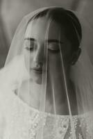 artistique portrait de une magnifique la mariée avec mariage coiffure et maquillage en dessous de une voile. noir et blanc photo