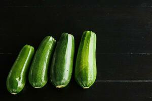 quatre vert Frais Zucchini sur une noir Contexte. concept de en bonne santé en mangeant photo