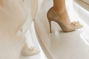 couleur or talon haut des chaussures avec Swarovski des pierres. le la mariée grimpe le escaliers photo