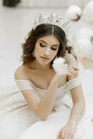 studio photo de une Princesse dans une mariage robe avec une luxueux coiffure et se maquiller, le la mariée est séance à le table